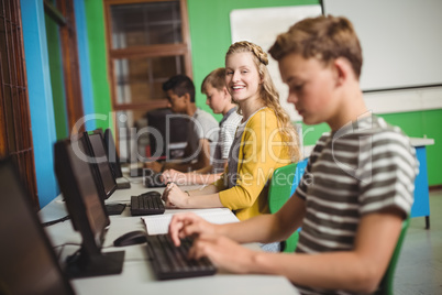 Smiling students studying in computer classroom