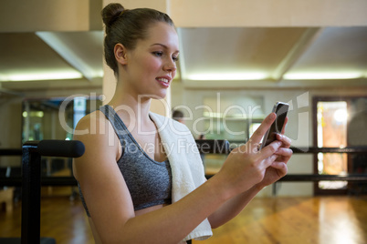 Beautiful fit woman using mobile phone after workout