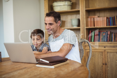 Father and son using laptop in study room