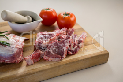 Rib chop, stone grinder and tomatoes on wooden board