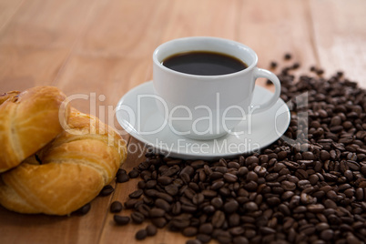 Coffee with roasted coffee beans and croissant