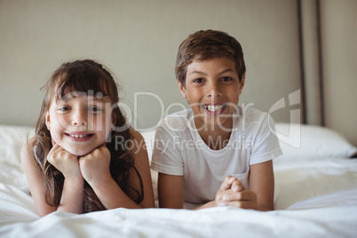 Siblings smiling in bed