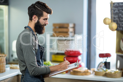 Salesman writing on clipboard at counter