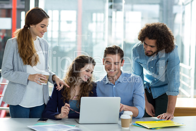 Smiling business team discussing over laptop in meeting