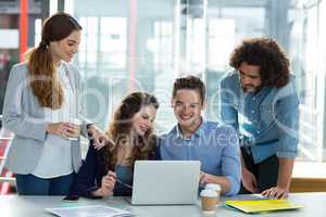 Smiling business team discussing over laptop in meeting