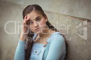 Anxious teenage girl leaning on wall