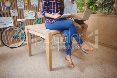 Graphic designers sitting on desk using laptop and digital tablet