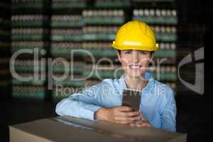 Female factory worker holding mobile phone in factory