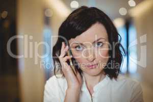 Portrait of female business executive talking on mobile phone in corridor