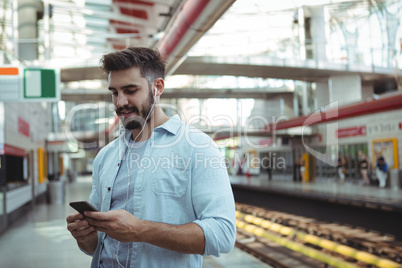 Smiling executive listening music while using mobile phone