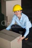 Portrait of female factory worker picking up cardboard boxes