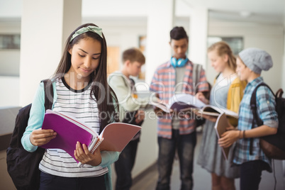 Schoolgirl standing in corridor reading notebook