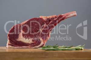Rib chop steak and rosemary herb on wooden board against grey background