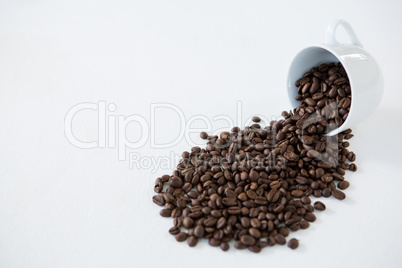 Roasted coffee beans spilling out of cup