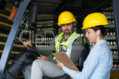 Factory workers checking record on clipboard in factory