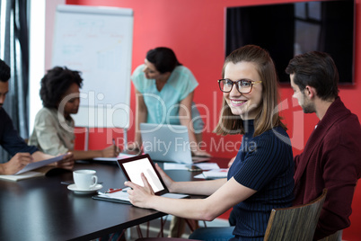 Portrait of business executive using digital tablet and colleague working in background