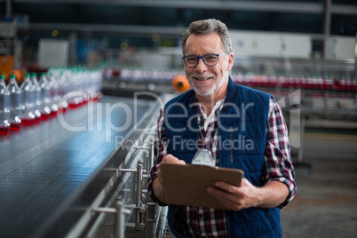 Portrait of smiling factory worker standing with a clipboard