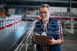 Portrait of smiling factory worker standing with a clipboard
