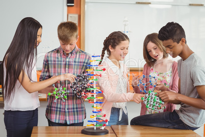 Happy school kids experimenting molecule model in laboratory