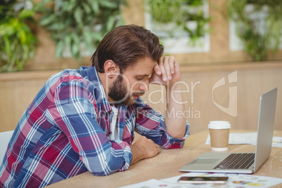 Tensed business executive with laptop siting at desk