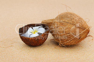 coconut and magnolia flower on a background of a sandy beach