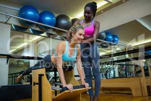Trainer assisting woman with wunda chair in fitness studio