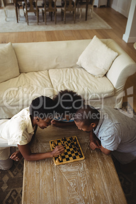 Family playing chess together at home in the living room