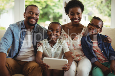Parents and son using digital tablet on sofa in living room