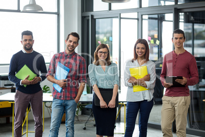 Smiling businesspeople standing with file and clipboard in office