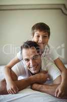 Father and son smiling while lying on bed