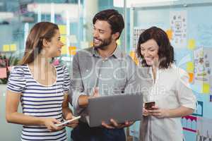 Team of business executives discussing over laptop