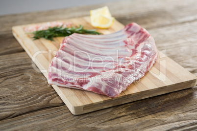 Beef ribs, rosemary herb, salt and lemon on wooden board