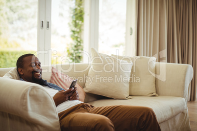 Man sitting on sofa and using mobile phone in living room Man sitting on sofa and using mobile phone in living room