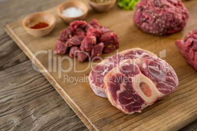Varieties of meat and spices on wooden tray
