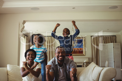 Parents and kids having fun while watching television in living room