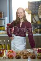 Shop assistant standing at the counter with oil bottle, pickle and bread