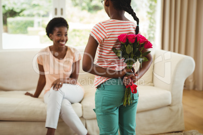 Daughter hiding flowers behind her back for mother