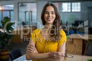 Female designer standing with arms crossed in creative office