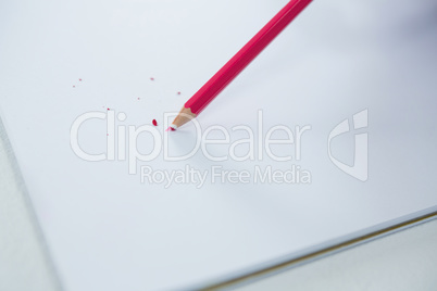 Red colored pencil with broken tip with notebook
