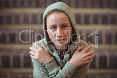Portrait of sad schoolgirl sitting alone on staircase