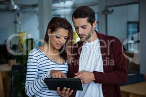 Man and woman discussing over digital tablet