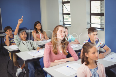 School kids raising hand in classroom