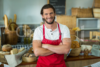 Portrait of smiling bakery staff standing with arms crossed at counter