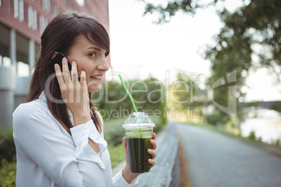 Executive talking on mobile phone while having juice