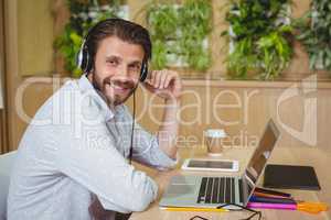 Portrait of male business executive sitting with laptop and listening song