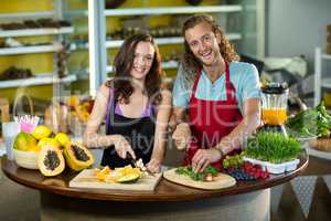 Two shop assistant chopping vegetables and fruits at counter