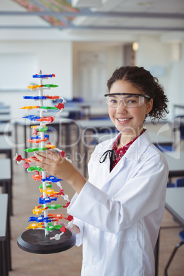 Portrait of happy schoolgirl experimenting molecule model in laboratory