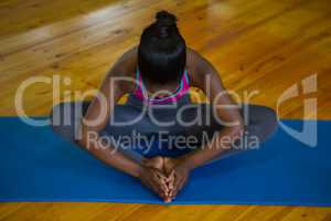 Fit woman doing stretching exercise on mat