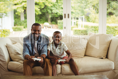 Portrait of father and son playing video game in living room