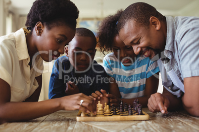 Family playing chess together at home in the living room